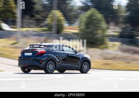 Ein SUV-Auto in Schwarz, das tagsüber mit hoher Geschwindigkeit auf der Straße fährt. Nahaufnahme, Bewegungsunschärfe, Konzepte. Stockfoto