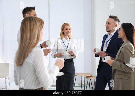 Gruppe von Personen, die sich während der Kaffeepause drinnen unterhalten Stockfoto