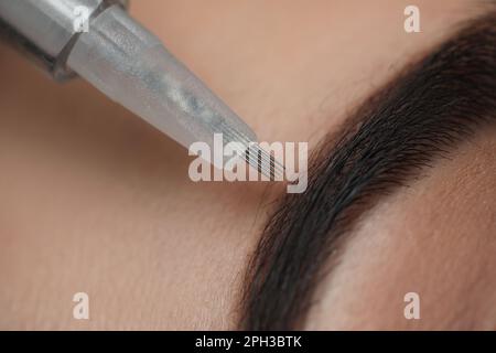 Junge Frau, die sich einer permanenten Augenbrauen-Make-up-Operation unterzieht, im Salon, Nahaufnahme Stockfoto