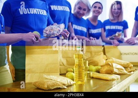 Doppelexposition von Freiwilligen, die Produkte für Flüchtlinge und ukrainische Flagge verpacken, Nahaufnahme. Hilfe während des Krieges Stockfoto