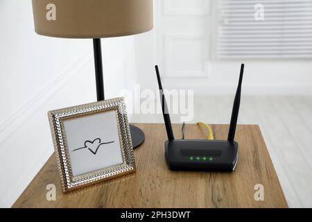 Moderner WLAN-Router auf Holztisch im Zimmer Stockfoto