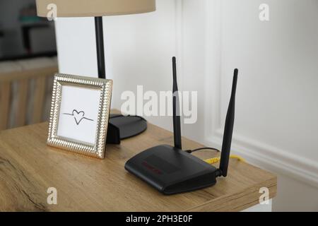 Moderner WLAN-Router auf Holztisch im Zimmer Stockfoto