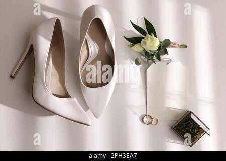 Wunderschöne Brautschuhe, Eheringe, Glasbox, Blume und Einladung auf weißem Hintergrund, Draufsicht Stockfoto
