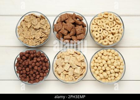 Verschiedene Frühstückszerealien in Glasschüsseln auf weißem Holztisch, flach liegend Stockfoto