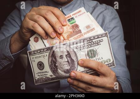 Die Hände nehmen russische Rubel aus der Brieftasche. Nahaufnahme der Hände eines Mannes, während er eine Banknote aus seinem Portemonnaie bekommt. Viel Geld. Ein reicher Mann. Einkommen Stockfoto