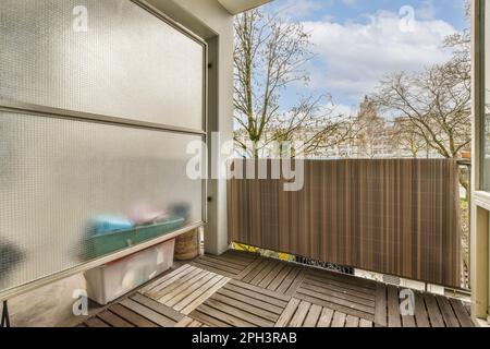 Ein Außenbereich mit Holzfußboden und Holzeinzäunung zwischen zwei Fenstern mit Blick auf die Straße Stockfoto