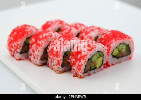 Traditionell köstliche frische Sushi-Brötchen auf schwarzem Hintergrund. Sushi-Brötchen mit Reis, Nori, Frischkäse, Tobikokaviar, Avocado. Sushi-Menü. Japanische Küche, Restaurant. Asiatisches Essen. Hohe Qualität Stockfoto