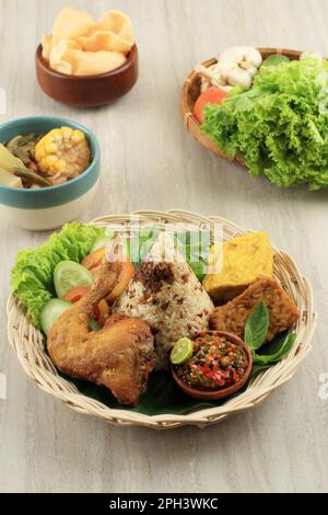 Nasi Tutug Oncom. Traditionelles Sundanesisches Gericht aus Reis gemischt mit fermentierten Sojabohnen, begleitet von Huhn, Sambal, Tofu und Tempeh Stockfoto