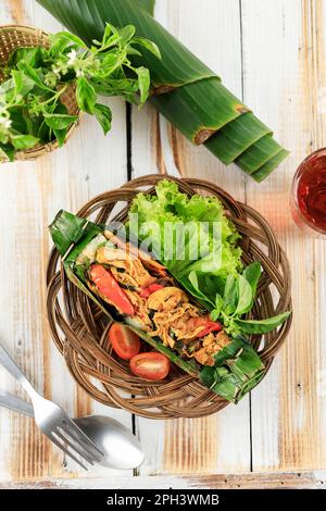 Nasi Bakar Ayam Suwir mit Kemangi, gedämpftem Reis mit gebratenem, würzigem Hähnchen und süßem Basilikumblatt, Umhang mit Bananenblatt und gegrilltem. Top Vie Stockfoto