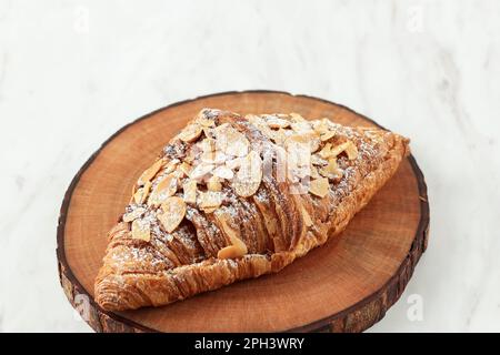 Mandel Croissant auf Holzplatte, isoliert auf Weiß Stockfoto