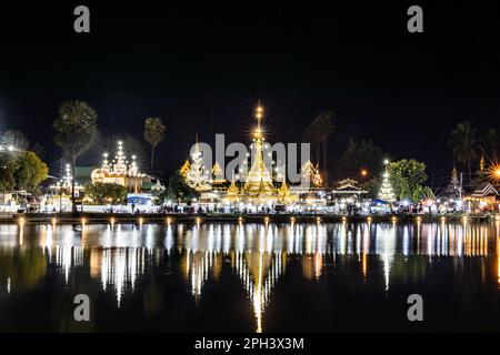 Gut beleuchteter Wat Chong Kham in Mae Hong Son Thailand bei Nacht, mit Reflexion vom See Stockfoto