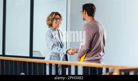 Einstellender Manager, der einem Kandidaten in einem Büro die Hand schüttelt. Weibliche HR-Fachkraft, die ein Meeting mit einem Bewerber abhält. Rekrutierung und Beschäftigung Stockfoto