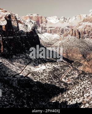 Blick auf den Zion Canyon mit Blick auf den Highway 9, während die kurvige Straße wie ein Wanderweg den Canyon hinaufsteigt. Zion-Nationalpark im Winter mit Schnee. Stockfoto