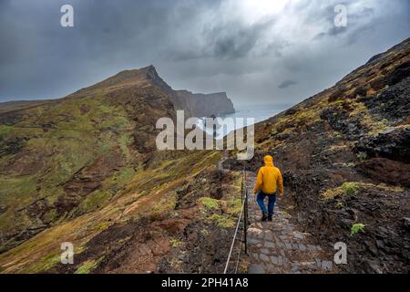 Wanderer auf dem Weg an der felsigen Landzunge, Küstenlandschaft mit roten Klippen und Meer, zerklüftete Küste mit Felsformationen, Cape Ponta de São Lourencalo, Madeira, Stockfoto