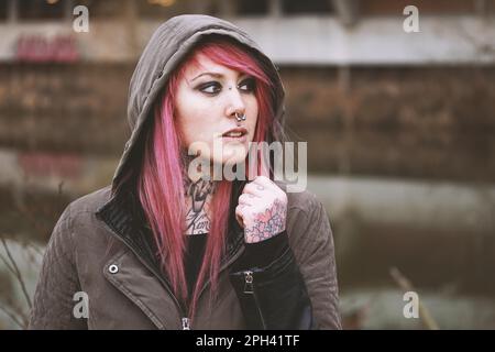 Porträt einer nachdenklichen jungen Frau mit Piercings und Tattoos Stockfoto