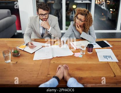 Sie sind fasziniert von den Fähigkeiten, die er der Firma bieten kann. Aufnahme von zwei Geschäftsleuten, die einen potenziellen Kandidaten für einen Job interviewen. Stockfoto