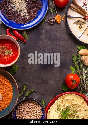 Traditionell für asiatische oder östliche Küche Getreidekörner, Bohnen, Gewürze auf bunten Tellern/Linsen, Reis, Kichererbse, Tomaten-Chutney, Pita. Zutaten Stockfoto