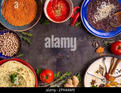 Traditionell für asiatische oder östliche Küche Getreidekörner, Bohnen, Gewürze auf bunten Tellern/Linsen, Reis, Kichererbse, Tomaten-Chutney, Pita. Zutaten Stockfoto