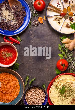 Traditionell für asiatische oder östliche Küche Getreidekörner, Bohnen, Gewürze auf bunten Plateaus Lentil, Reis, Kichererbse, Tomaten-Chutney, Pita. Zutaten Stockfoto