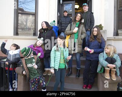 Die Nachbarn sehen die St. Patrick's Day Parade von ihrer treppe aus in Park Slope, Brooklyn, NY Stockfoto