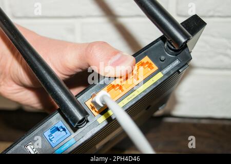 WLAN-Router, Rückseite des Routers, halten Sie den Router mit den Kabeln in der Hand Stockfoto