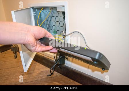 Offene Box zum Router, menschliche Hand hält schwarzen Router Stockfoto