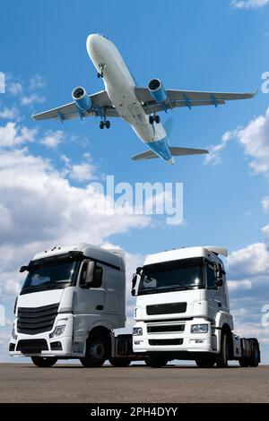 Ein Flugzeug am Himmel über den Lastwagen. Welthandel- und Transportkonzept Stockfoto