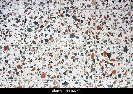 Die Textur von Terrazzo-Keramikfliesen, viele verschiedene granulare Einschlüsse von mehrfarbigen Kieseln. Stockfoto