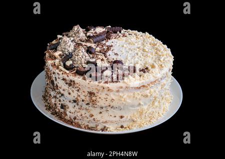 Hausgemachter, von Hand zubereiteter Schwammkuchen, dekoriert mit Schokolade, Krümeln und Waffeln. Kuchen auf einem weißen Teller, isolieren Stockfoto