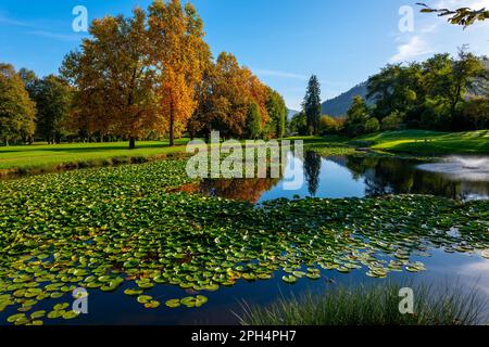 Golfplatz mit Wasserteich und Herbstbäumen an einem sonnigen Tag in Lugano, Tessin, Schweiz. Stockfoto