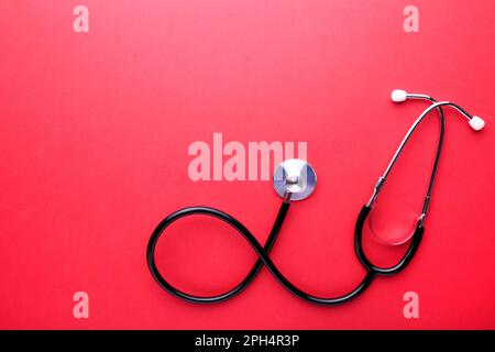Medizinisches Stethoskop auf rotem Hintergrund mit Kopierraum Stockfoto