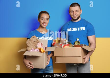 Freiwillige, die Spendenboxen mit ukrainischer Flagge im Hintergrund halten. Hilfe während des Krieges Stockfoto