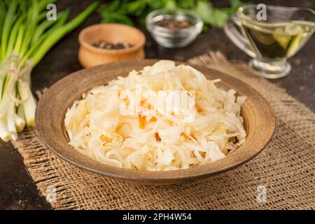 Sauerkraut mit Karotten in einer Schüssel. Fermentiertes Futter. Hausgemachtes Essen. Eingelegtes Essen. Eingelegtes Gemüse. Vegetarisches veganes Essen. Seitenansicht . Stockfoto