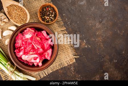 Kohlsalat mit Rüben in einer Tonschüssel. Fermentierte Lebensmittel. Hausgemachtes Essen. Saure Nahrung. Eingelegtes Gemüse. Vegetarisches veganes Essen. Draufsicht, flach liegend. Polizist Stockfoto