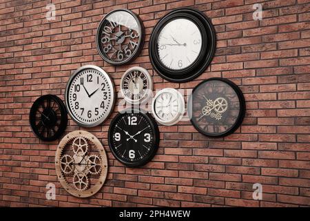 Uhrensammlung an roten Backsteinwänden Stockfoto