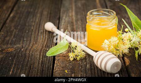 Lindenblumen und Lindenhonig auf einem Holztisch. Pflanzliche Medizin. Alternativmedizin. Seitenansicht. Banner. Speicherplatz kopieren. Stockfoto