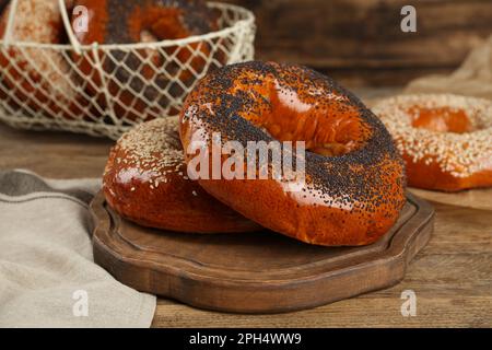 Köstliche frische Bagels mit Mohn- und Sesamsamen auf einem Holztisch Stockfoto