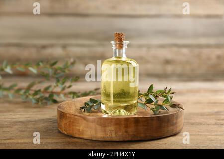 Flasche ätherisches Eukalyptusöl und Pflanzenzweige auf Holztisch Stockfoto