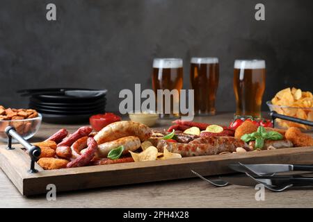 Verschiedene leckere Snacks und Bier auf einem Holztisch Stockfoto