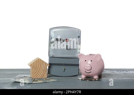 Stromzähler, Hausmodell, Geld und Sparschwein auf grauem Holztisch vor weißem Hintergrund Stockfoto