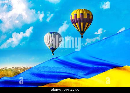 Doppelte Belichtung der ukrainischen Flagge und farbenfrohe Heißluftballons am blauen Himmel Stockfoto