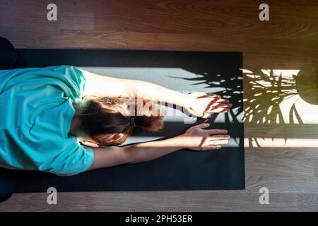 Selbstliebe mit gesundem Lebensstil, weibliche Person auf Yogamatte zu Hause. Stockfoto