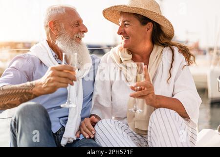 Seniorenpaar, das während der Sommerferien Champagner auf dem Segelboot trinkt - Fokus auf Frauengesicht Stockfoto