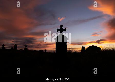 Grabstein-Silhouetten am Cross Abbey Friedhof nach Sonnenuntergang, Mullet Halbinsel, County Mayo, Irland Stockfoto