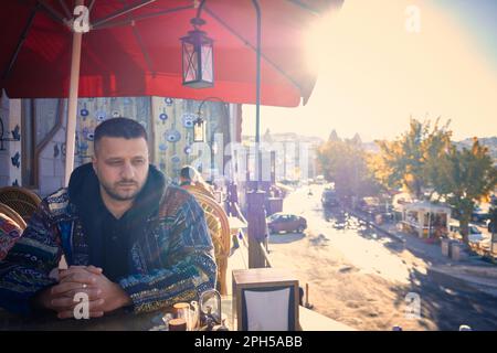 Der Mann sitzt im Café im Freien Stockfoto