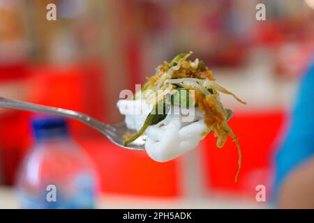 Nahaufnahme eines kleinen Metalllöffels voller Reis und Gemüse. Bokeh-Hintergrund. Stockfoto