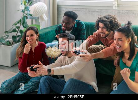 Eine Gruppe von Freunden spielt zu Hause gemeinsam Videospiele, um Spaß zu haben. Stockfoto