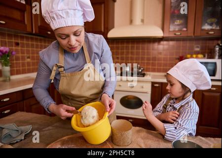 Gezielter Fokus auf eine hübsche Frau, die ihrer Tochter Kochen beibringt, Teig knete und gleichzeitig festlichen Osterkuchen zubereitete Stockfoto