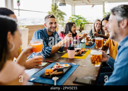 Eine Gruppe junger Studentenfreunde, die zusammen im Café zu Mittag essen Stockfoto