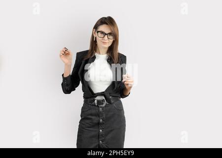 Kaukasische erfolgreiche selbstbewusste junge Geschäftsfrau in formeller Kleidung und Brille. Bankangestellter oder Lebensversicherungsvertreter mit grauem Hintergrund Stockfoto